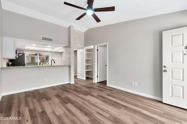 unfurnished living room featuring lofted ceiling, hardwood / wood-style floors, a tray ceiling, and ceiling fan