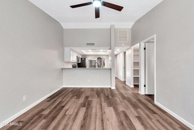 unfurnished living room with ceiling fan, high vaulted ceiling, and dark hardwood / wood-style flooring