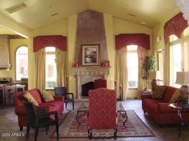 living room with a fireplace with raised hearth and high vaulted ceiling