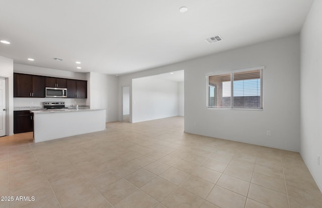 kitchen featuring stainless steel appliances, visible vents, open floor plan, dark brown cabinets, and light countertops