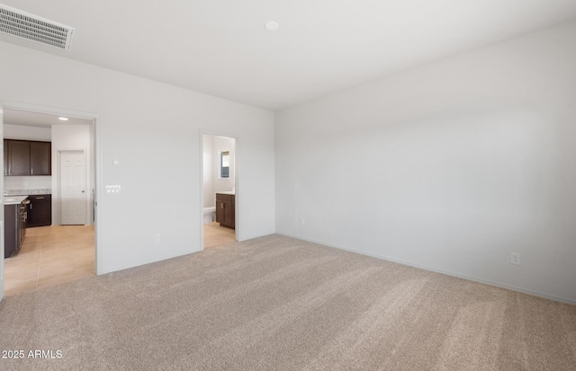 interior space featuring light carpet, visible vents, and connected bathroom