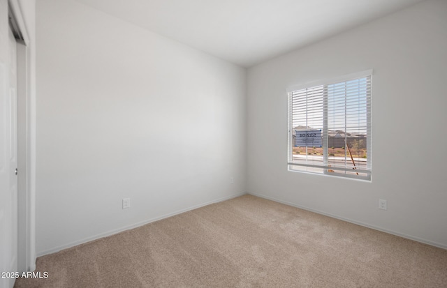 empty room featuring light carpet and baseboards