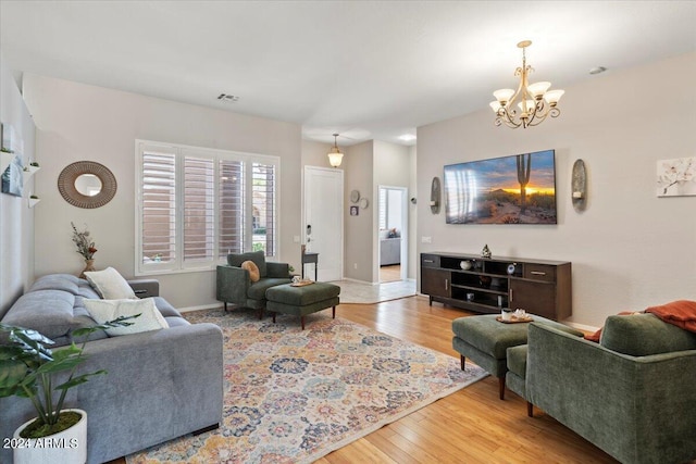 living room with light hardwood / wood-style floors and a notable chandelier