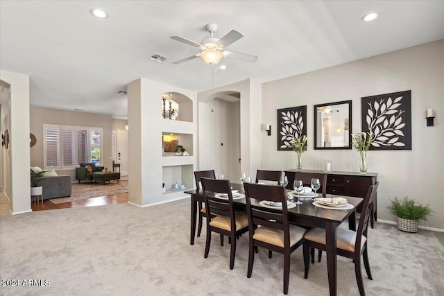 dining area featuring built in shelves, light carpet, and ceiling fan