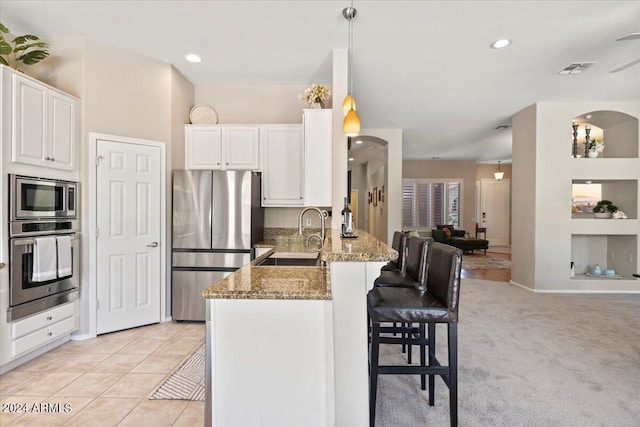 kitchen featuring kitchen peninsula, appliances with stainless steel finishes, light carpet, sink, and pendant lighting