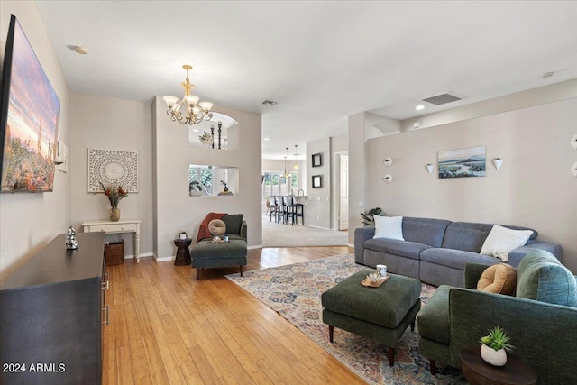 living room with light hardwood / wood-style floors and an inviting chandelier