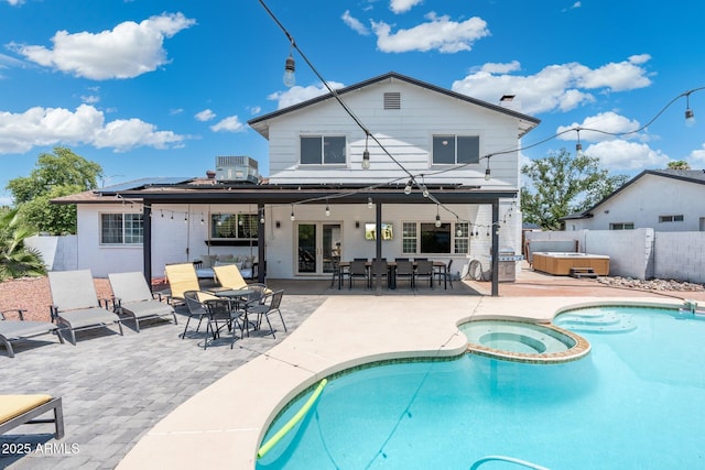 back of house featuring central AC unit, fence, solar panels, a hot tub, and a patio area