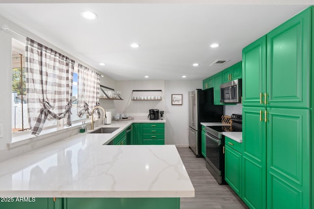 kitchen featuring sink, green cabinets, stainless steel appliances, light stone countertops, and light hardwood / wood-style flooring