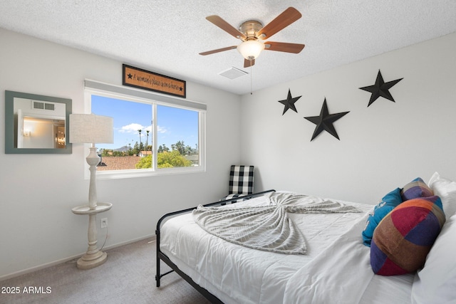 bedroom with ceiling fan, carpet flooring, and a textured ceiling