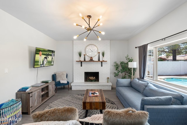 living room featuring an inviting chandelier, a brick fireplace, and hardwood / wood-style floors