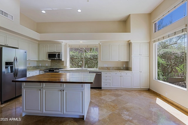 32710 N 71st St, Scottsdale, AZ 85266 - kitchen with appliances with stainless steel finishes, butcher block countertops, a center island, a towering ceiling, and white cabinets