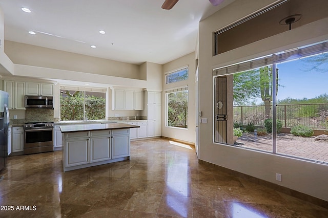 32710 N 71st St, Scottsdale, AZ 85266 - kitchen featuring appliances with stainless steel finishes, a towering ceiling, tasteful backsplash, a center island, and recessed lighting