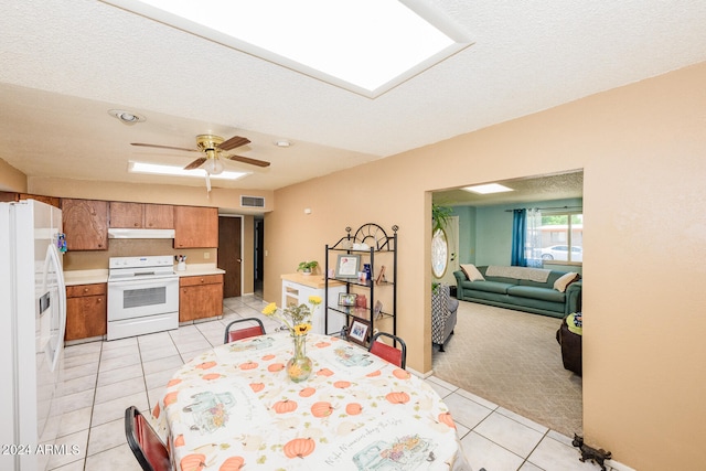 tiled dining area with ceiling fan and a textured ceiling