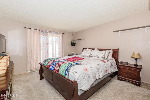 bedroom featuring light carpet and a textured ceiling