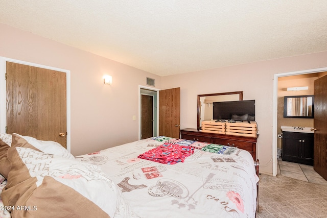 carpeted bedroom featuring sink, connected bathroom, and a textured ceiling