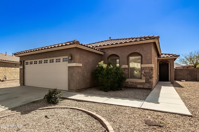 mediterranean / spanish-style home featuring a garage, concrete driveway, a tiled roof, and stucco siding