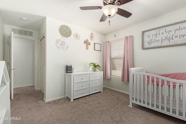 carpeted bedroom with a ceiling fan, a nursery area, visible vents, and baseboards