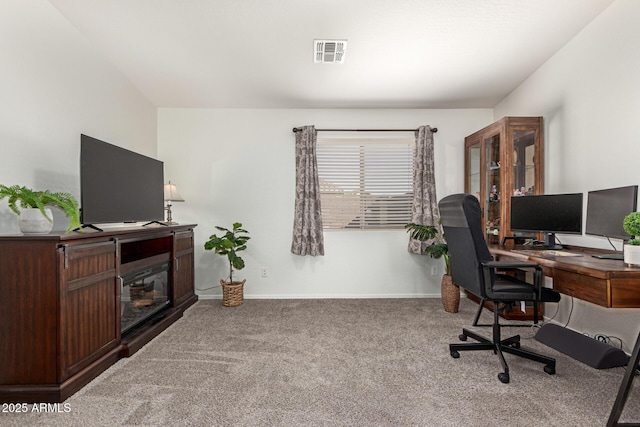 office space with carpet, a glass covered fireplace, visible vents, and baseboards