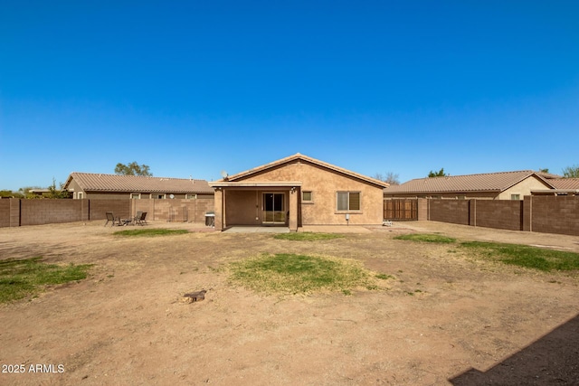 rear view of house with stucco siding, a fenced backyard, and a patio