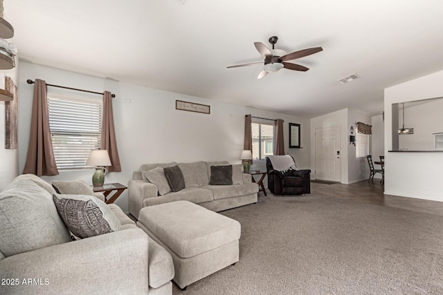 living area with carpet, visible vents, and ceiling fan