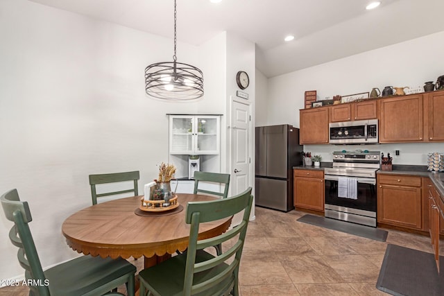 kitchen with dark countertops, brown cabinets, stainless steel appliances, and lofted ceiling