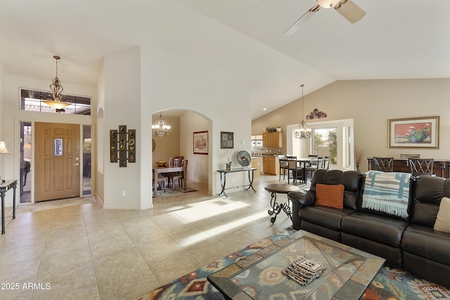 tiled living room with ceiling fan with notable chandelier and high vaulted ceiling