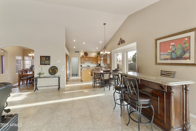 interior space featuring high vaulted ceiling, an inviting chandelier, and light tile patterned flooring