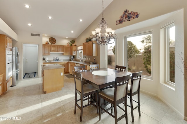 dining space with sink, high vaulted ceiling, an inviting chandelier, and light tile patterned floors