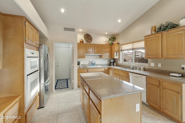 kitchen with white appliances, lofted ceiling, sink, a kitchen island, and light tile patterned flooring