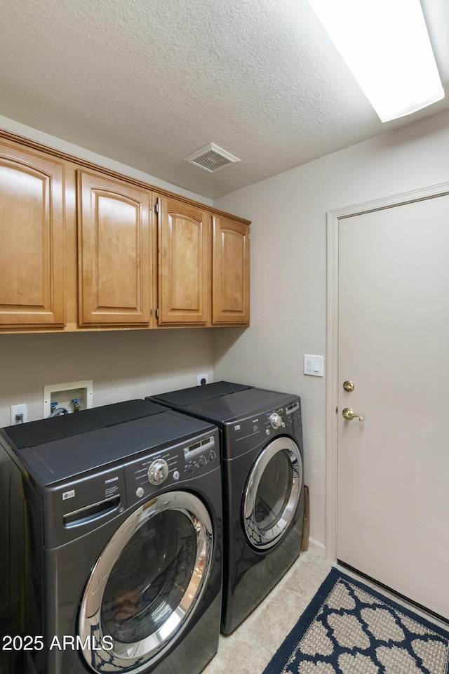 laundry room with cabinets, a textured ceiling, and washing machine and clothes dryer