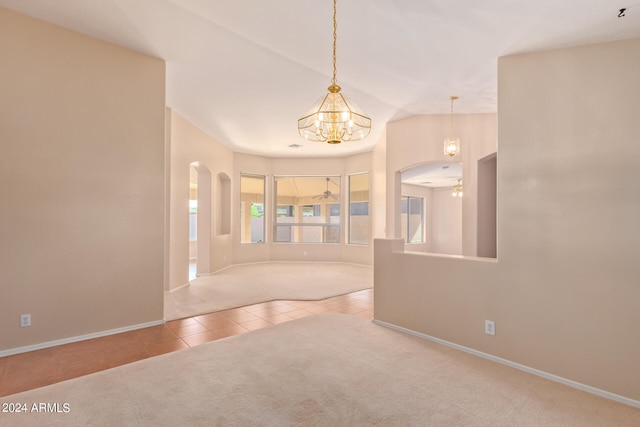 unfurnished room with vaulted ceiling, ceiling fan with notable chandelier, and light tile patterned floors