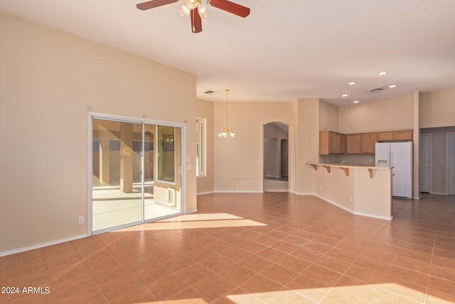 unfurnished living room with light tile patterned floors and ceiling fan with notable chandelier