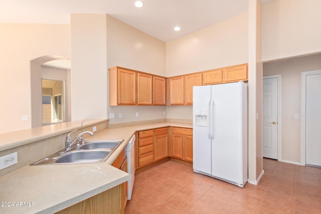 kitchen with kitchen peninsula, high vaulted ceiling, light tile patterned flooring, sink, and white appliances