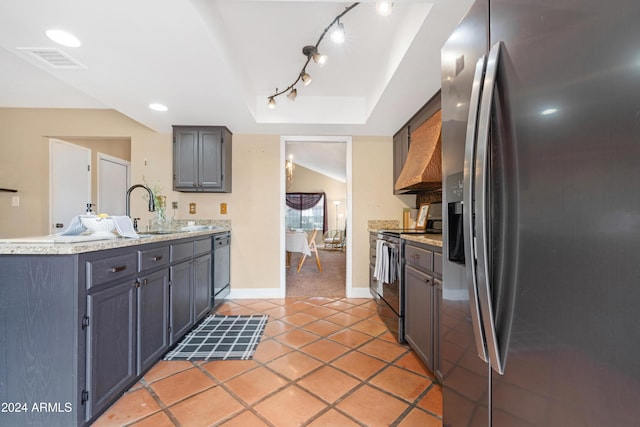 kitchen featuring a tray ceiling, sink, light tile patterned flooring, and appliances with stainless steel finishes