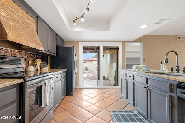 kitchen with appliances with stainless steel finishes, a tray ceiling, extractor fan, sink, and gray cabinets