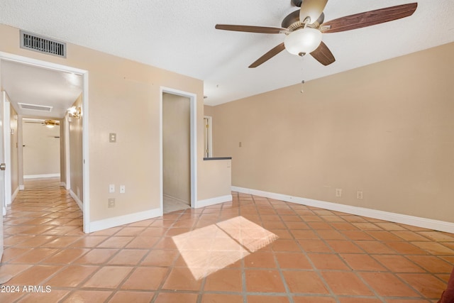 spare room with ceiling fan, tile patterned flooring, and a textured ceiling