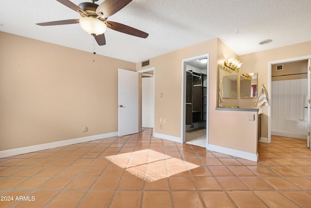 interior space with ceiling fan, light tile patterned flooring, and a textured ceiling