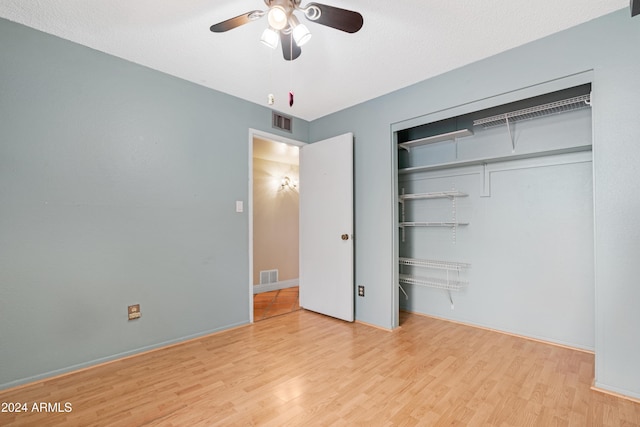 unfurnished bedroom featuring ceiling fan, a closet, light hardwood / wood-style floors, and a textured ceiling