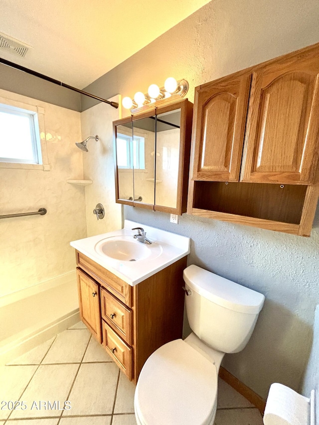 bathroom with vanity, tile patterned floors, toilet, and tiled shower