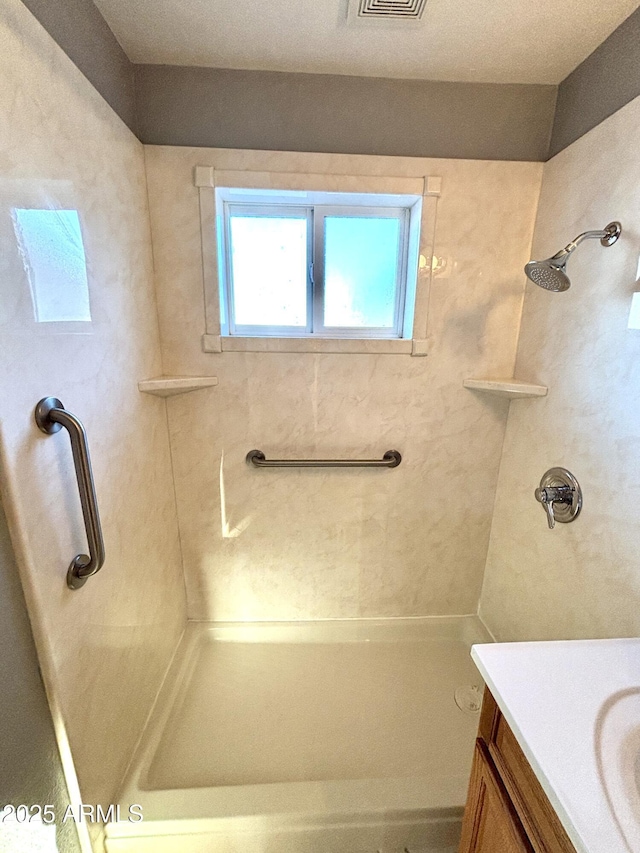 bathroom with tiled shower and vanity