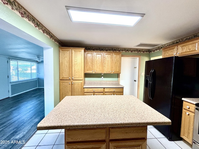 kitchen with black fridge with ice dispenser, stainless steel electric range oven, ceiling fan, and a kitchen island