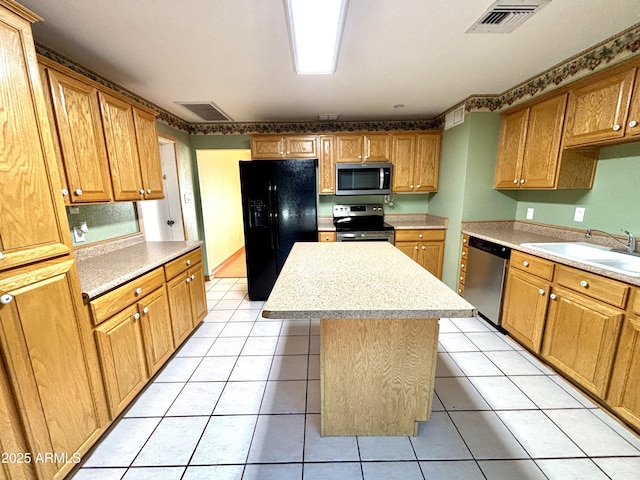 kitchen featuring light tile patterned flooring, appliances with stainless steel finishes, a center island, and sink