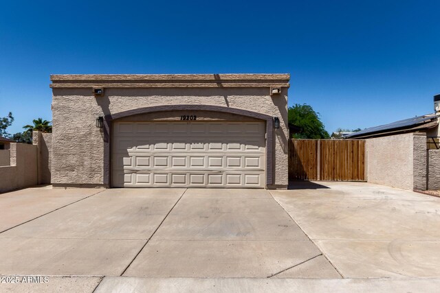 garage featuring concrete driveway and fence