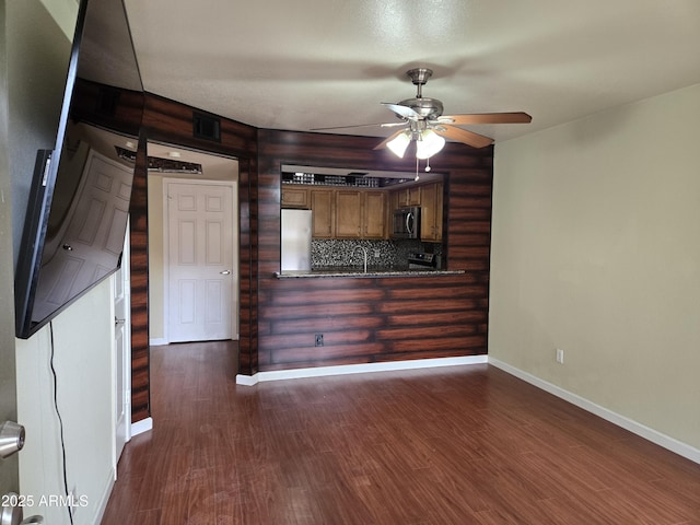 unfurnished living room featuring visible vents, dark wood-type flooring, a sink, baseboards, and ceiling fan