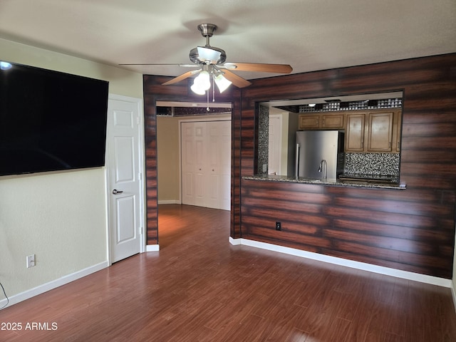 interior space with indoor wet bar, baseboards, wood finished floors, and a ceiling fan