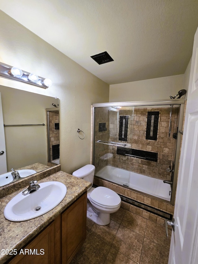 bathroom with tile patterned floors, toilet, vanity, and tiled shower / bath