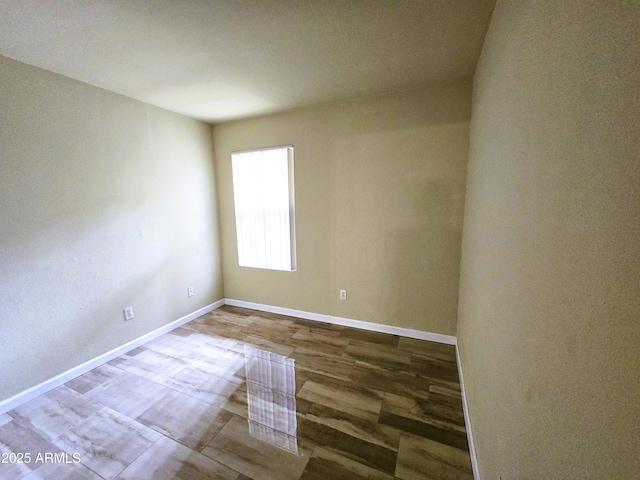 spare room with baseboards and wood finished floors