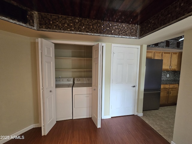 clothes washing area with laundry area, dark wood-style flooring, baseboards, and separate washer and dryer