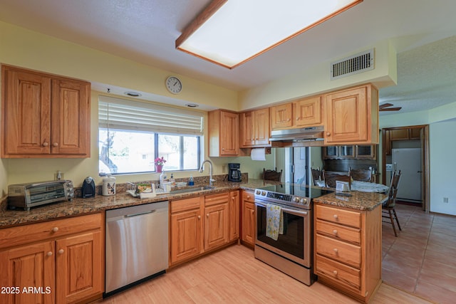 18622 E Via De Arboles, Queen Creek, AZ 85142 - kitchen featuring visible vents, under cabinet range hood, a sink, stainless steel appliances, and dark stone counters