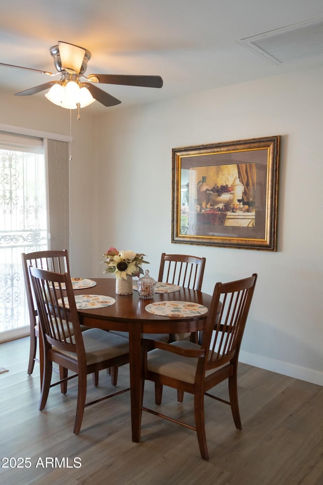 dining space featuring wood finished floors, a ceiling fan, visible vents, and baseboards